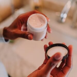 Person Holding a Plastic Container with Cream and a Lid